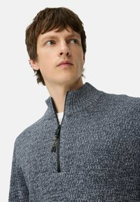 Getextureerde mid-zip breipullover in donkergrijs. Beschikt over een hoge kraag en contrasterende rits met zwarte hardware, gemaakt van zacht materiaal.