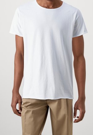 Weißes T-Shirt aus leichtem Baumwollmaterial mit Rundhalsausschnitt, kurzen Ärmeln und legerer Passform, kombiniert mit beigen Hosen. Glatte Textur, minimalistisches Design.