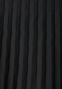 Detail černé látky s vertikálním ribkovaným vzorem, kde se střídají vystouplé a prohloubené pruhy.