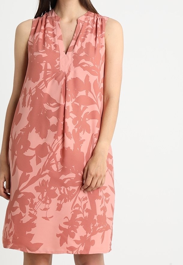 Ärmelloses Kleid aus weichem rosa Stoff mit einem floralen Muster in dunklerem Farbton. Lockerer Schnitt mit V-Ausschnitt und subtilen Raffungselementen.
