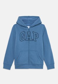 Blå dragkedja huvtröja med framfickor, fleecefoder inuti huvan och stora konturerade "GAP"-bokstäver på bröstet.