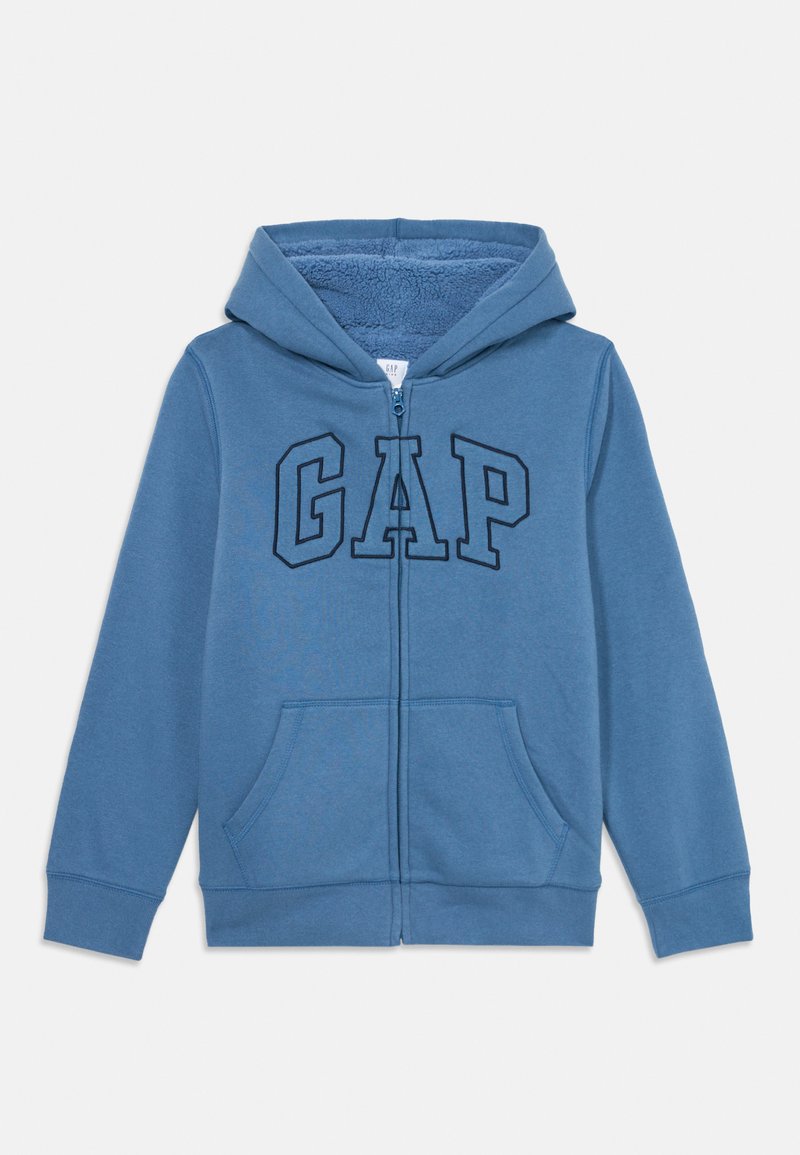 Blå dragkedja huvtröja med framfickor, fleecefoder inuti huvan och stora konturerade "GAP"-bokstäver på bröstet.