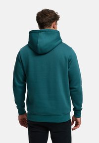 Sudadera con capucha azul verdoso, con capucha grande, puños y cinturilla acanalados. Textura suave con detalles de costuras en los hombros y la espalda.