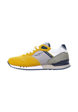 Baskets jaunes et grises avec un dessus en suède texturé, des lacets blancs et un accent bleu marine au niveau du talon. Comprend des panneaux en mesh et une semelle rembourrée.