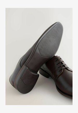 Chaussures de ville en cuir marron avec une finition lisse, un laçage et des semelles en caoutchouc texturé pour plus d'adhérence.