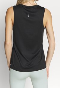 Černý sportovní top bez rukávů z hladké látky, s kulatým výstřihem a minimalistickým bílým švem na zádech.