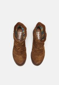Botines de ante marrón con un diseño fruncido, que cuentan con un forro de rayas multicolores. Puntera redondeada y suela plana con detalles de costura.