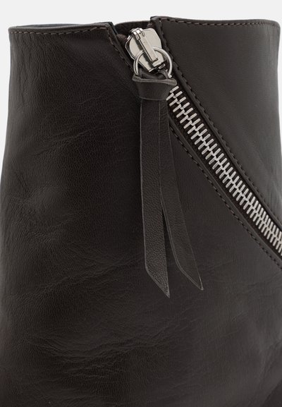 Svart läderankelstövel med en sidoslidsknäppning med silverdetaljer och en platt profil. Materialet har en lätt texturerad yta.