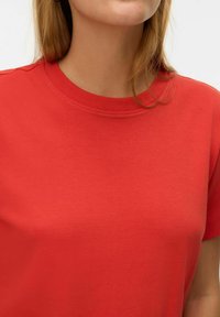 Rød kortærmet t-shirt med rund halsudskæring, glat stoftekstur og en tætsiddende pasform, ideel til afslappet brug.