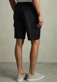 Sorte cargo-shorts lavet af letvægtsstof, med to sidelommer, elastisk talje og en skræddersyet pasform. Sættes sammen med sko i neutrale toner.