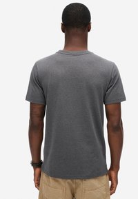 Grå kortærmet t-shirt med rund hals og glat tekstur. Bagsiden har en subtil buet kant med en afslappet pasform.