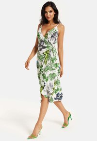 Wrap dress made of lightweight fabric, featuring a white base with green and blue tropical leaf patterns, and a knee-length asymmetrical hem.
