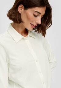 Witte blouse met knoopsluiting en kraag, gemaakt van een gladde stof. Kenmerkt zich door zichtbare knopen en een ontspannen pasvorm met lange mouwen.