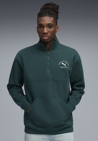 Donkergroene pullover sweatshirt met een kwart rits, een voorkantzak en het 'PUMA ATHLETICS' logo in het wit, met een zachte textuur.