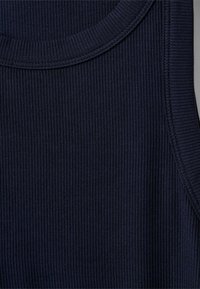 Tengerészkék bordázott ujjatlan felső kerek nyakkivágással és texturált anyaggal. A dizájn kiemeli a függőleges csíkokat és a testhezálló szabást.