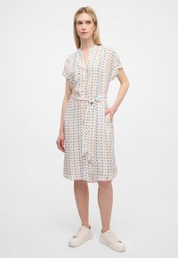 Abito a fantasia con tessuto leggero caratterizzato da un design geometrico multicolore, maniche corte, colletto e cintura annodata in vita.