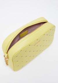 Borsa cosmetica sintetica gialla con design trapuntato, dettagli in strass, cerniera dorata e fodera interna marrone. Presenta un'etichetta con il logo.