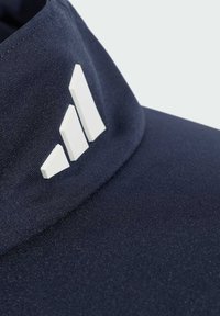 Granatowa czapka z teksturowanej tkaniny z białym logo w trzy paski z przodu; ma zakrzywiony daszek i wzmocnione szwy.