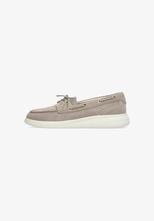 Chaussure bateau en daim marron clair avec semelle blanche, lacets à l'avant et œillets latéraux, vue de profil sur fond blanc.