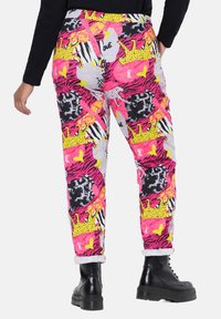 Mehrfarbige Hose mit einer Mischung aus Tiermotiven, Herzen und Kronen in Pink, Gelb und Schwarz. Mit aufgerollten Säumen und einem lässigen Schnitt.
