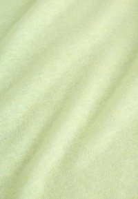 Tissu jaune doux avec une texture fine tricotée et des plis doux créant des ombres et des reflets subtils.