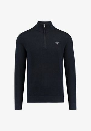 Pull bleu marine à manches longues avec un col montant, fermeture éclair mi-zippée, tissu texturé et un petit logo brodé sur la poitrine.