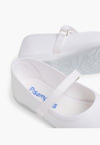 Białe baletki na płaskim obcasie z paskiem na kostce, zaokrąglonym noskiem i teksturowaną podeszwą. Logo "Pisamonas" nadrukowane na niebiesko wewnątrz.