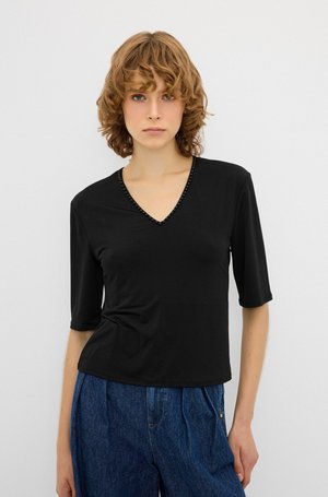 Top negro de manga corta con cuello en V y detalles decorativos de cuentas a lo largo del escote, fabricado en una tela suave y ligera.