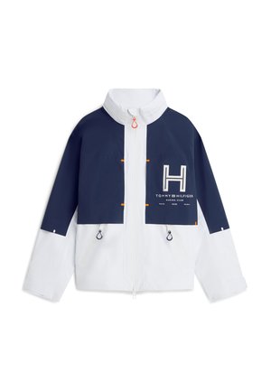 Veste zippée bleu marine et blanche avec col haut, poches poitrine, tirettes de zip noires et logo Tommy Hilfiger Marina Club sur le devant.