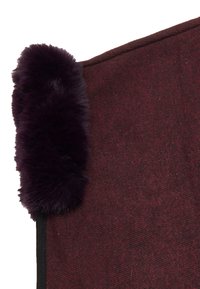 Burgunderfarbener Stoff mit strukturiertem Finish, an einer Kante mit einem dunkellila Kunstfellakzent und einem glatten schwarzen Rand.