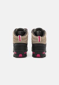 Scarponi da trekking alti con tomaia in suede color tan, dettagli in gomma nera e particolari rosa. Suole testurizzate e collari imbottiti migliorano il supporto.
