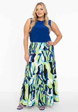 Blauwe mouwloze top gecombineerd met een gelaagde maxi rok met een levendig abstract patroon in groen, blauw en zwart. Blauwe sandalen met bandjes.