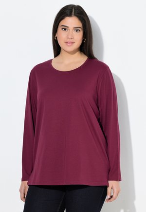 Chemise bordeaux à manches longues en tissu doux avec un col rond et une coupe décontractée, assortie à un jean foncé. Design simple sans motifs visibles.