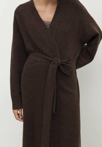 Manteau enveloppant marron à manches longues en tissu texturé, avec une ceinture à nouer à la taille et des poignets côtelés, présentant un décolleté en V.