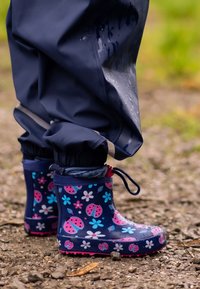 Rubberen regenlaarzen met een donkerblauwe basis en roze lieveheersbeestje- en bloemenpatronen. Waterdicht ontwerp met een gestructureerde zool voor grip.