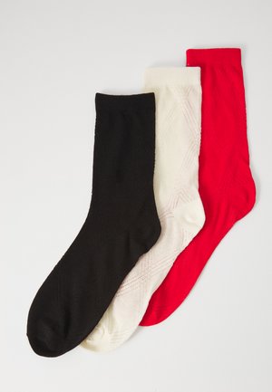 Three pairs of knitted socks: black, white, and red, featuring a diagonal pattern, with a smooth texture and a mid-calf length.