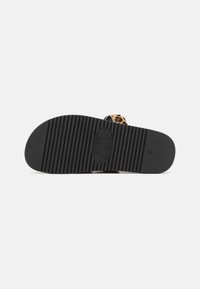 Black rubber sole with textured grooves for traction, combined with a leopard print strap. Circular logo on the insole.