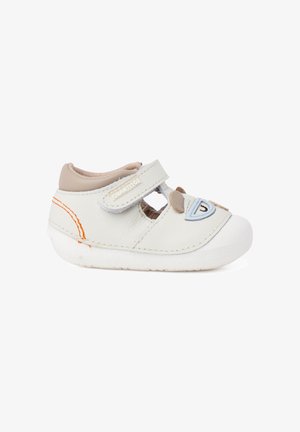 Chaussure blanche pour tout-petit avec col beige, surpiqûres orange, bride à scratch et motif visage d'ours ludique à l'avant.
