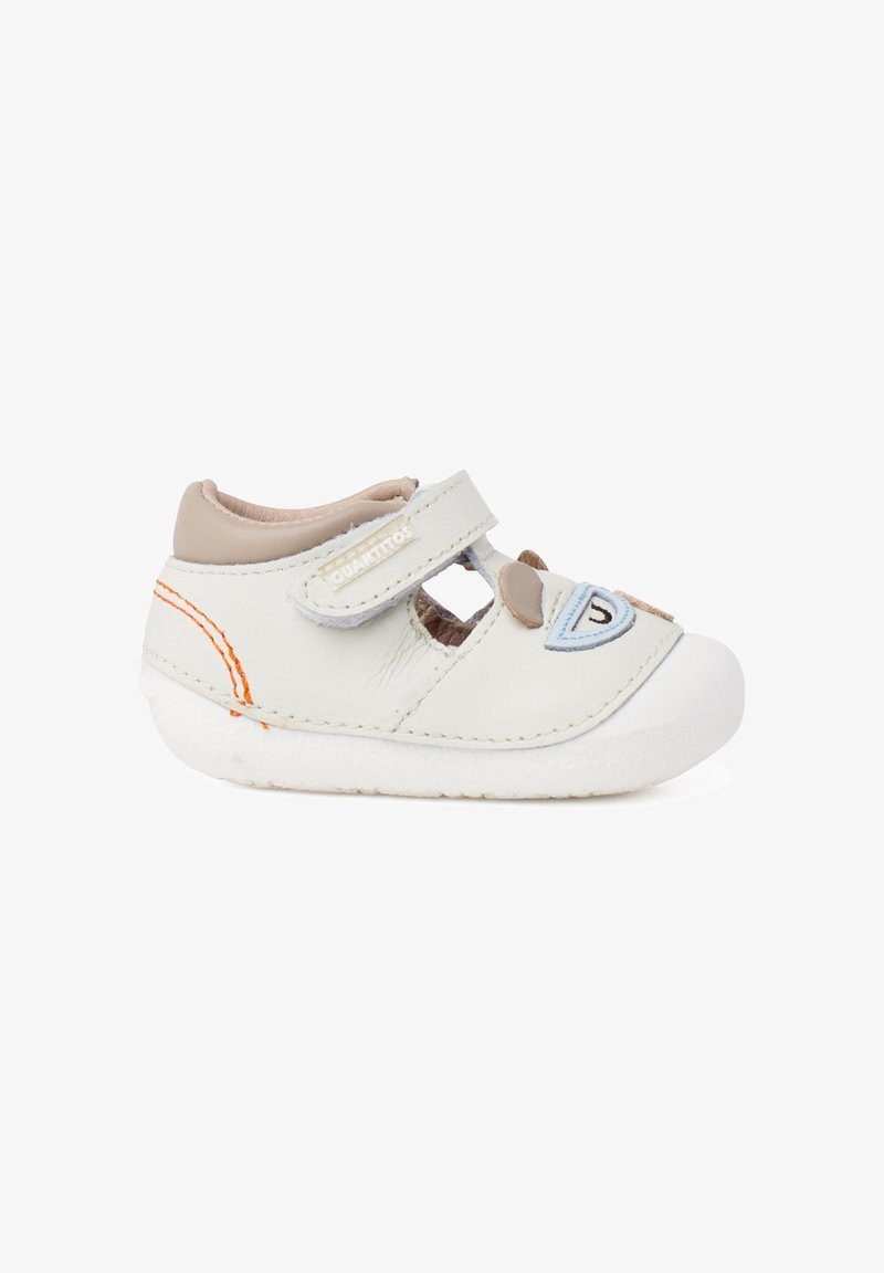 Chaussure blanche pour tout-petit avec col beige, surpiqûres orange, bride à scratch et motif visage d'ours ludique à l'avant.