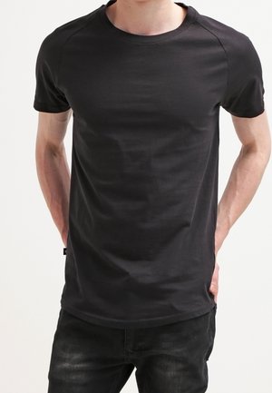 Zwart T-shirt met korte mouwen, een ronde hals en raglanmouwen, gemaakt van glad katoenen stof, met een licht gebogen zoom.
