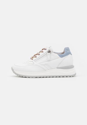 Biały sneaker z szarą podeszwą, niebieską zamszową patką na pięcie, wielokolorowymi sznurowadłami i bocznym zamkiem na prostym jasnym tle.
