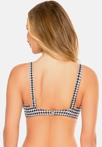 Schwarzes und weißes Hahnentrittmuster-Bikini-Oberteil mit verstellbaren Trägern, Häkchenverschluss und glatter Stoffoberfläche, von hinten betrachtet.