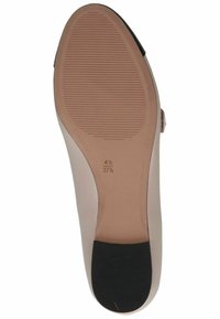 Suela de zapato de color beige claro y suave, con ranuras texturizadas para proporcionar agarre y un acento en el talón negro; las marcas de tamaño son visibles.