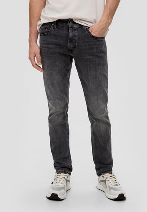 Jean en denim noir avec une coupe slim, léger délavage et design à cinq poches. Associé à des baskets de sport blanches avec des accents en mesh.