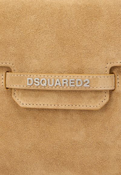 Δερμάτινο πουγκί από σουέντ σε ανοιχτό μπεζ χρώμα με πλακέτα λογότυπου σε ασημί απόχρωση. Διαθέτει κλείσιμο με καπάκι και ορατές ραφές κατά μήκος των άκρων. Ομαλή υφή.