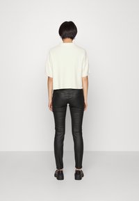 Suéter blanco cropped de mangas cortas combinado con pantalones negros ajustados. El conjunto cuenta con una textura suave y un diseño simple.