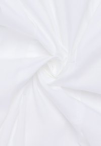 Tessuto bianco disposto a spirale, che mostra una texture liscia e un design semplice, con dettagli di cucitura visibili.