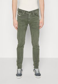 Zelena pamučna traperica slim fit kroja s dizajnom od pet džepova i blago teksturiranom završnom obradom. Sadrži kopčanje na gumb i patentni zatvarač s brendiranim detaljima.