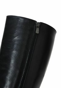 Stivale in pelle nera alto fino al ginocchio con zip laterale. Texture liscia e design elegante con un bordo superiore arrotondato. Accenti hardware minimalisti.