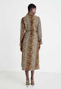 Abito a stampa leopardata con maniche lunghe, cintura in vita e design di lunghezza media realizzato in un tessuto morbido.